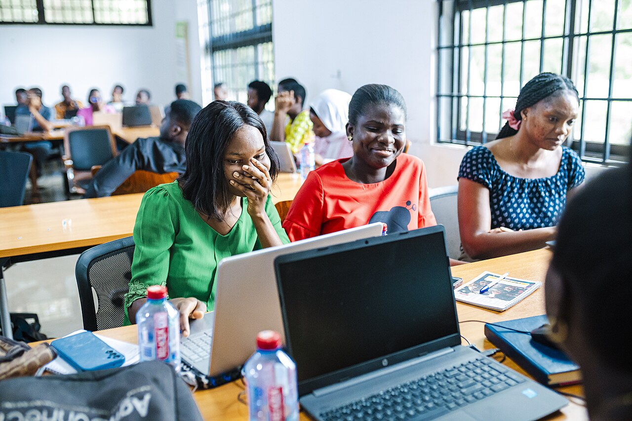 Young Ghanaian adults working together on laptops at a University of Ghana workshop